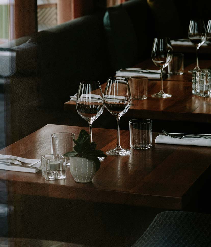 Restaurant with plush booths, wood tables, and elegant drink ware.