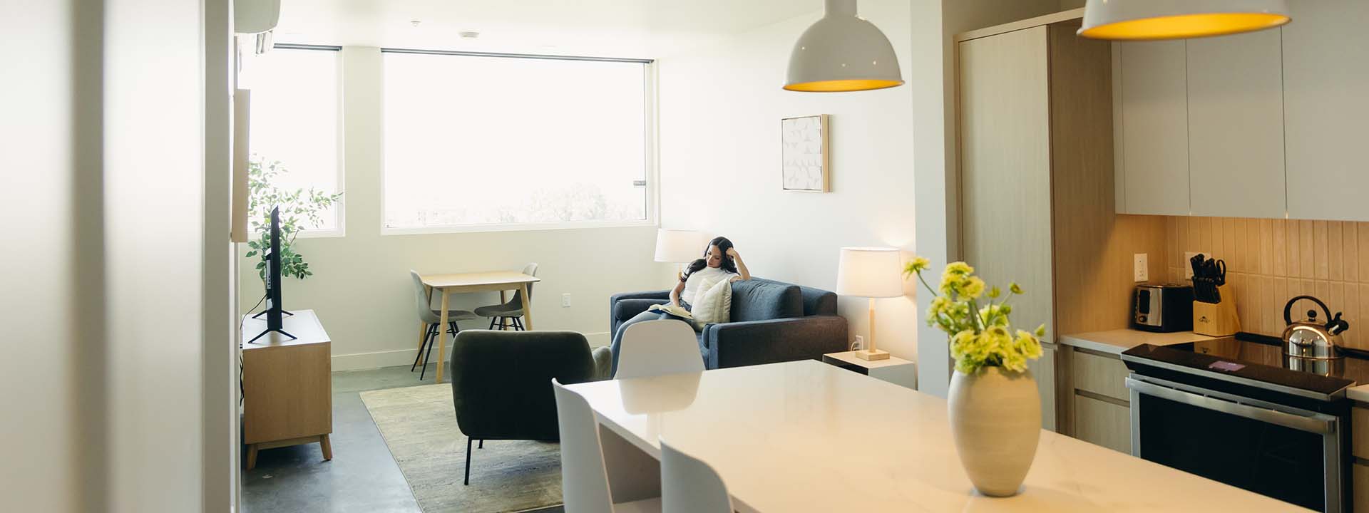 Brix apartment living area with comfortable seating, modern kitchen, and large windows.