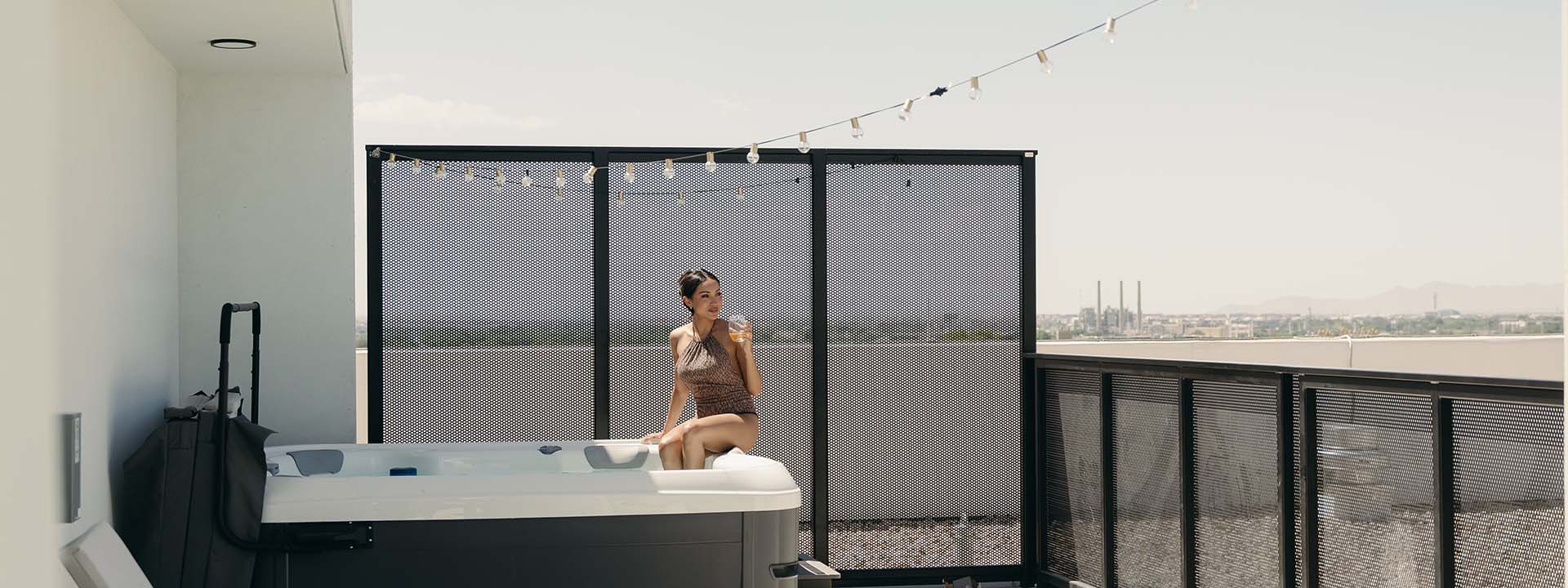 Person in swimsuit with drink sitting in roof top hot tub at Brix.