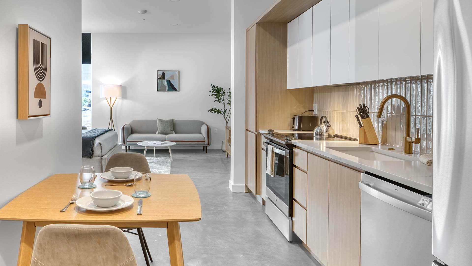 Brix apartment kitchen with polished concrete floor, light cabinets, and stainless steel appliances.